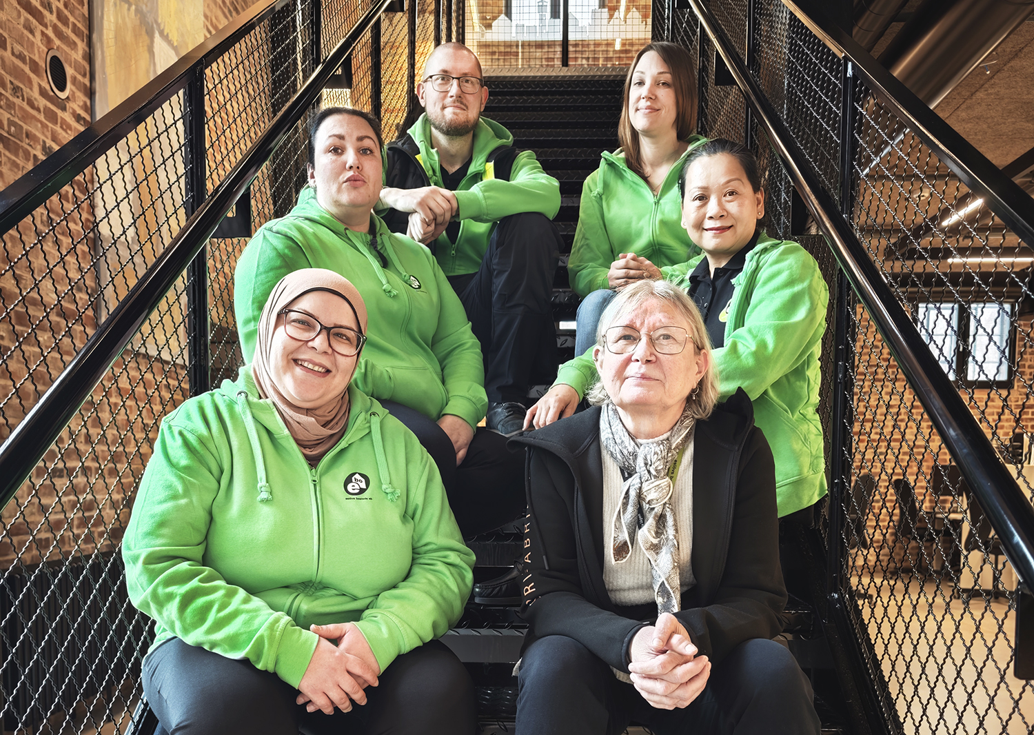 Sex personer som utgör Ebos städavdelning sitter i en trappa. 