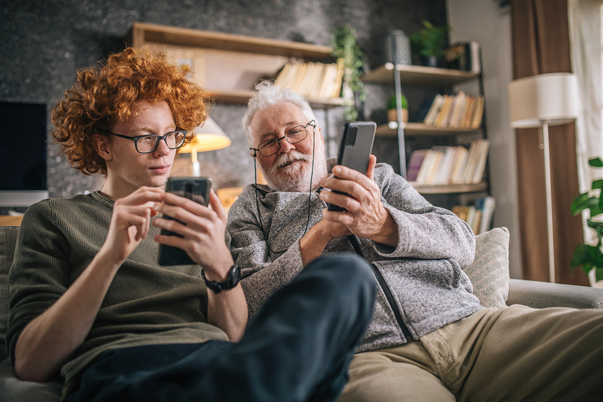Ung man och äldre man med varsin mobiltelefon.